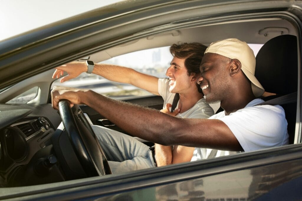 Cheerful multiracial young guys sharing car ride, travelling together