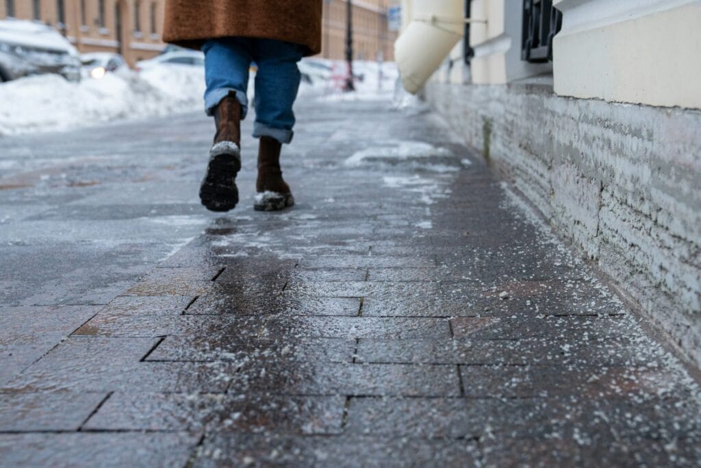 Technical salt grains on icy sidewalk surface in wintertime, used for melting ice and snow